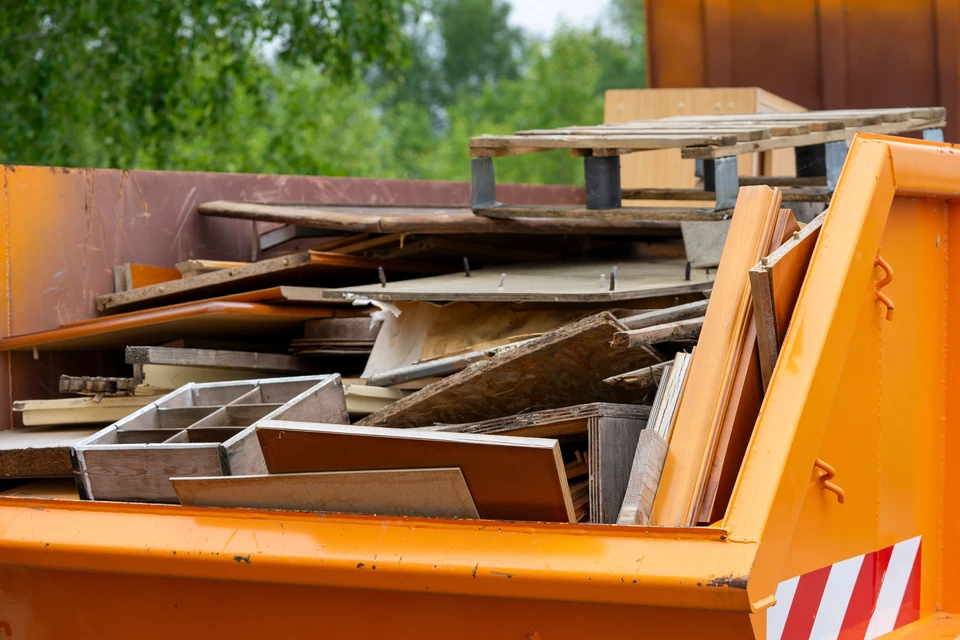 Scène extérieure avec deux compacteurs de déchets industriels stationnés sur une surface pavée, entourés d'arbres dénudés