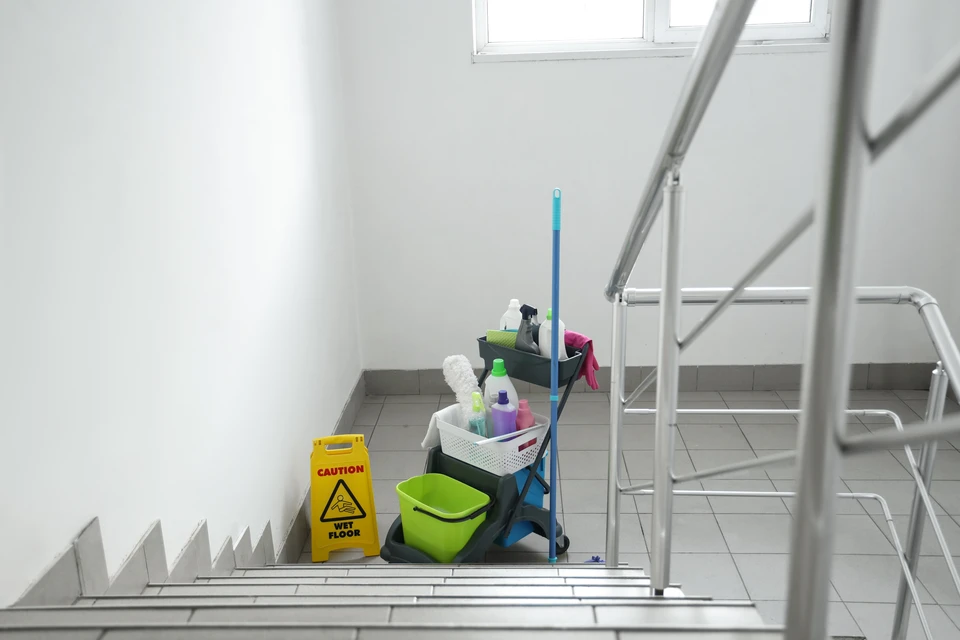 Équipe de nettoyage professionnel en uniformes bleus travaillant dans bureau moderne avec mur briques