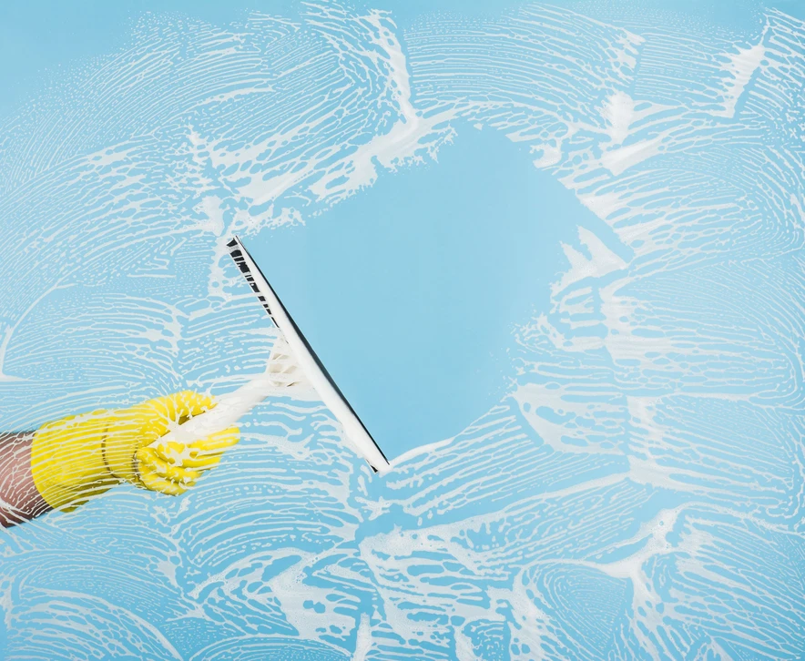 Nettoyage professionnel d'une surface vitrée avec raclette à manche télescopique