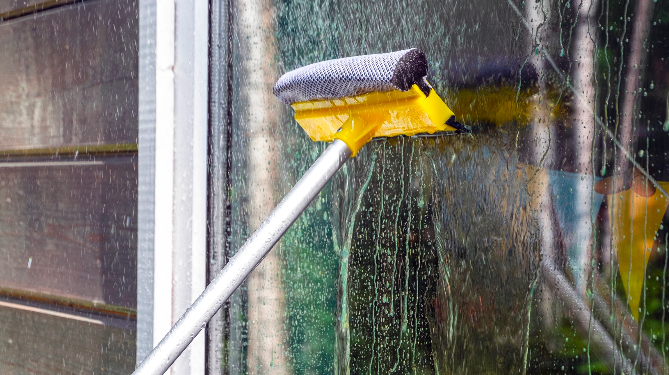 Deux professionnels nettoient de grandes baies vitrées dans un bureau moderne